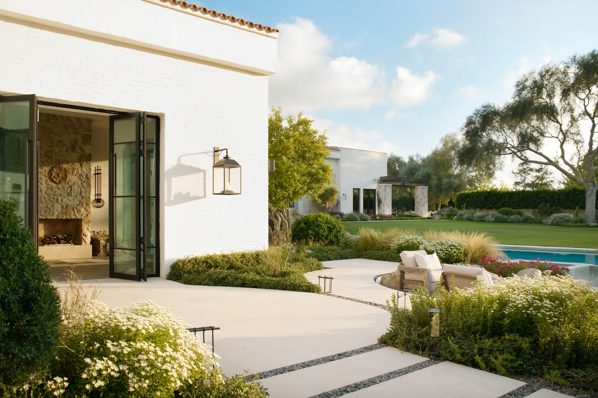 Outdoor wall lantern beside glass doors on a white brick home with garden, terrace and pool