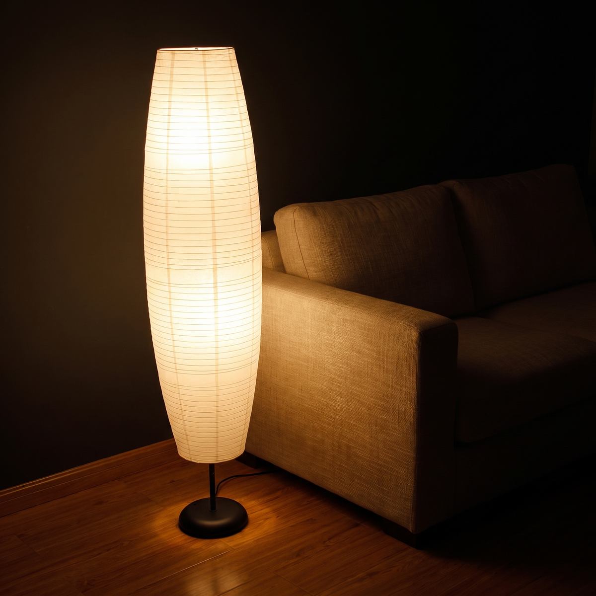 Rice paper column floor lamp lit in a dark living room
