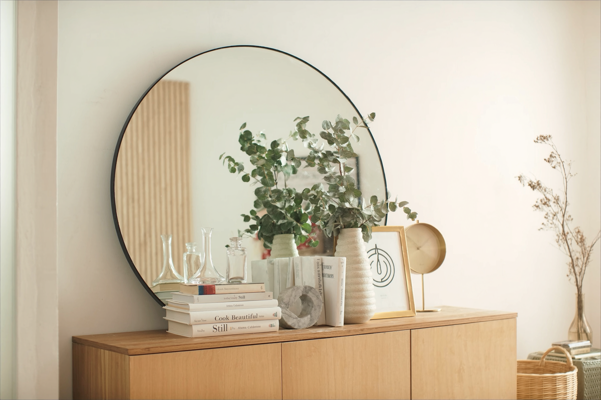 Home decor objects styled on an oak console beneath an arched mirror