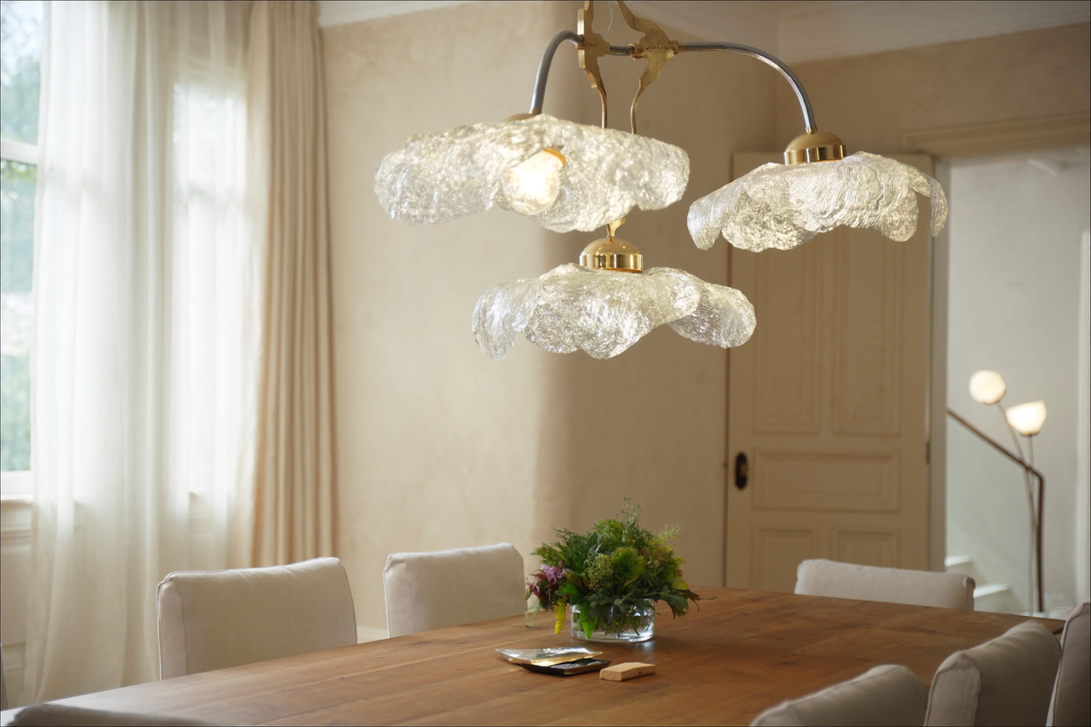 Glass and brass pendant lights over an oak dining table in a bright room