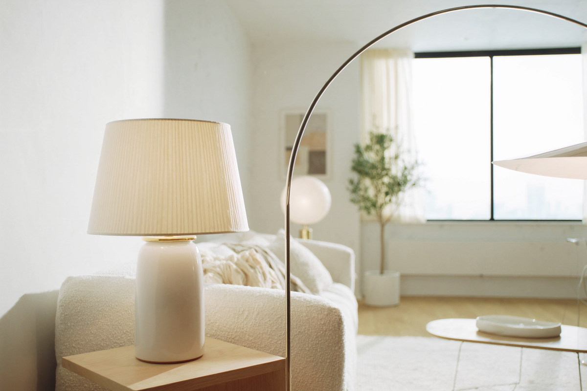 Ceramic table lamp and brass arc floor lamp in a sunlit living room
