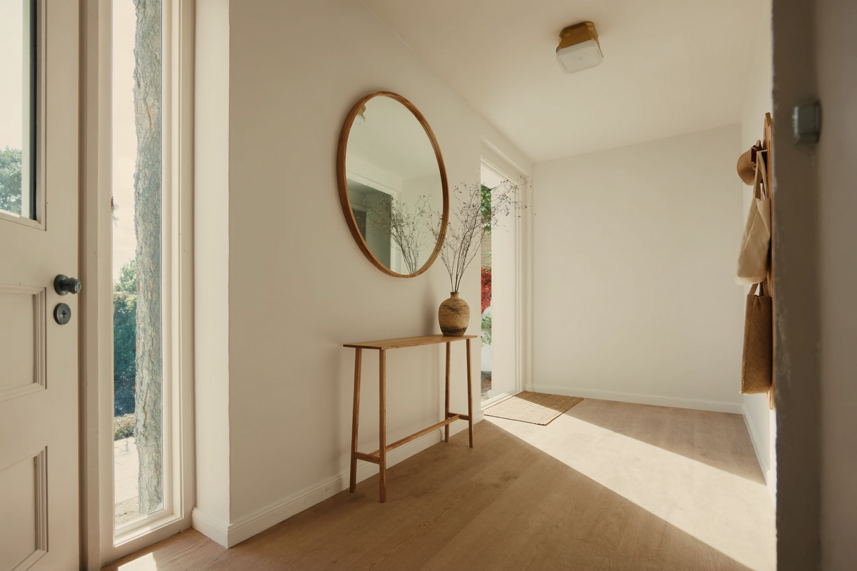 Bright entryway with an oak console, round mirror, coat rack and flush mount ceiling light